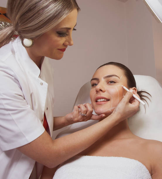 Home dermatologist woman surgeon drawing lines on woman